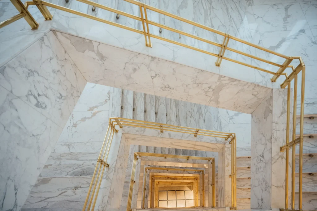 Looking up through a multi-level marble staircase with gold handrails, creating a geometric, spiral effect—an elegant scene perfect for showcasing exclusive Special Offers.