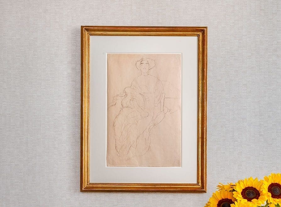 Gerahmte Bleistiftskizze einer sitzenden Person auf beigem Papier, die auf einer hellen, strukturierten Wand mit Sonnenblumen in der rechten unteren Ecke dargestellt ist.