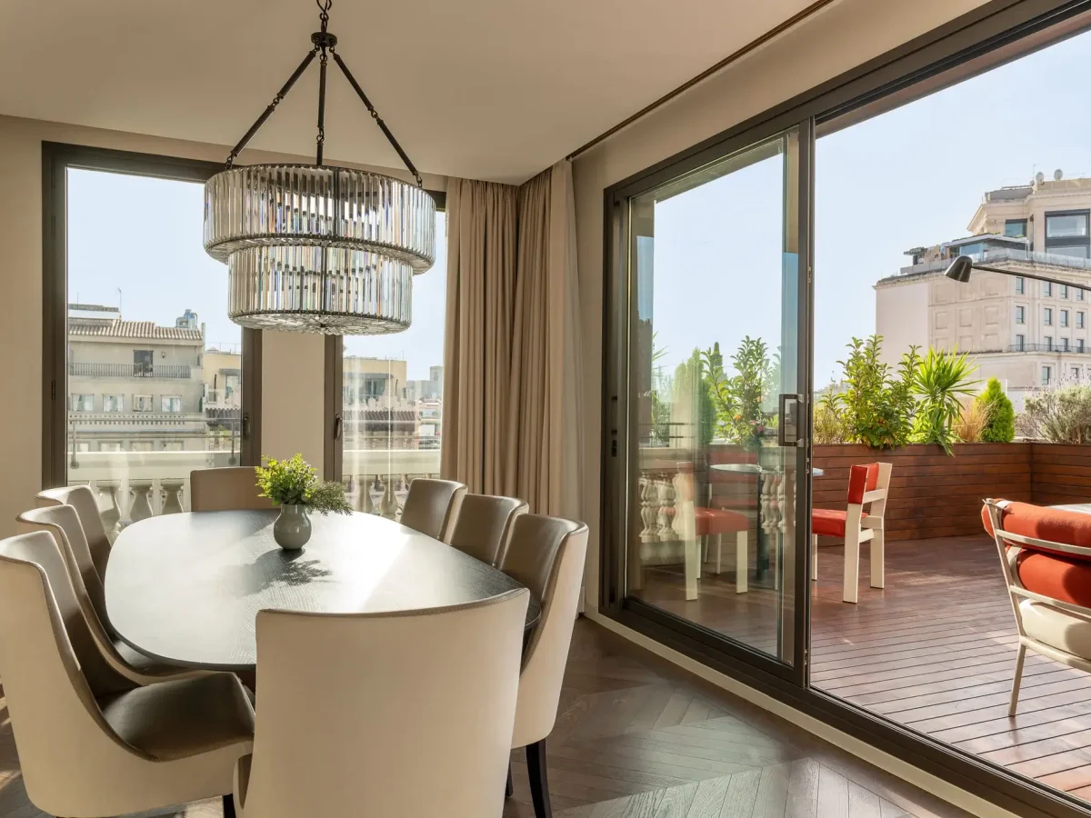 La suite Penthouse disposa d'una moderna zona de menjador amb una taula de vidre, cadires blanques i un llum d'aranya al costat de grans portes corredisses de vidre que donen a un balcó amb seients a l'aire lliure i impressionants vistes a la ciutat.