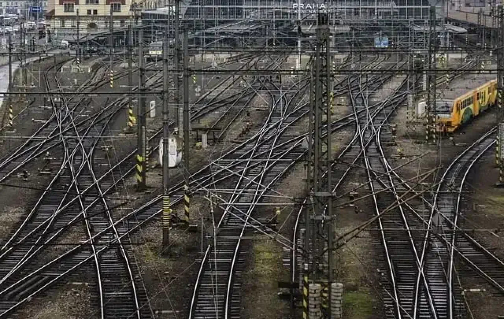 Multiple railway tracks converge and lead towards a historic train station with arched roofs and ornate buildings in the background, inviting travelers to experience the All Aboard Package.