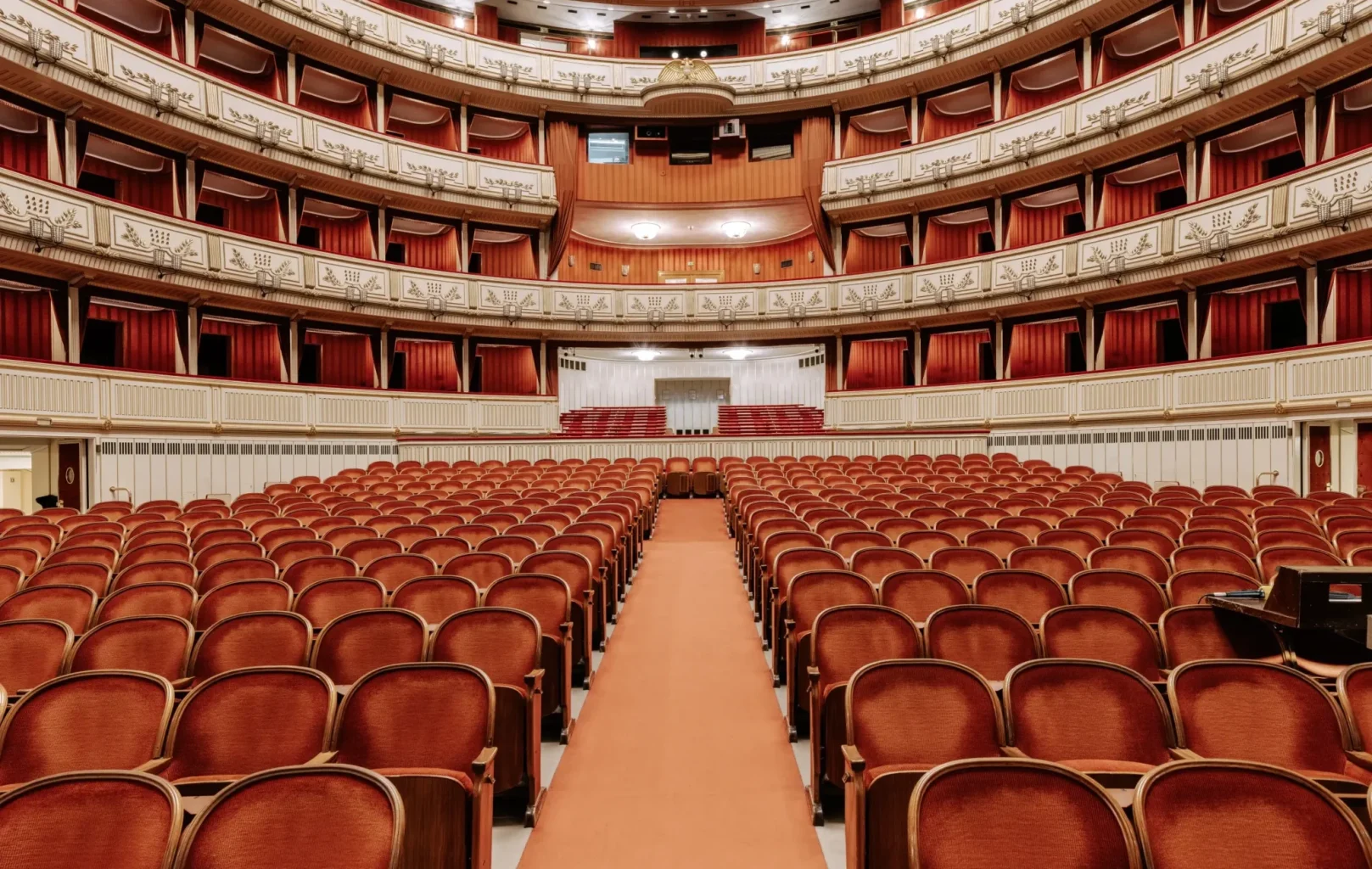 Interior view of an empty Opera House Vienna auditorium with rows of red seats, balconies, and ornate architectural details—a stunning example among Vienna attractions.