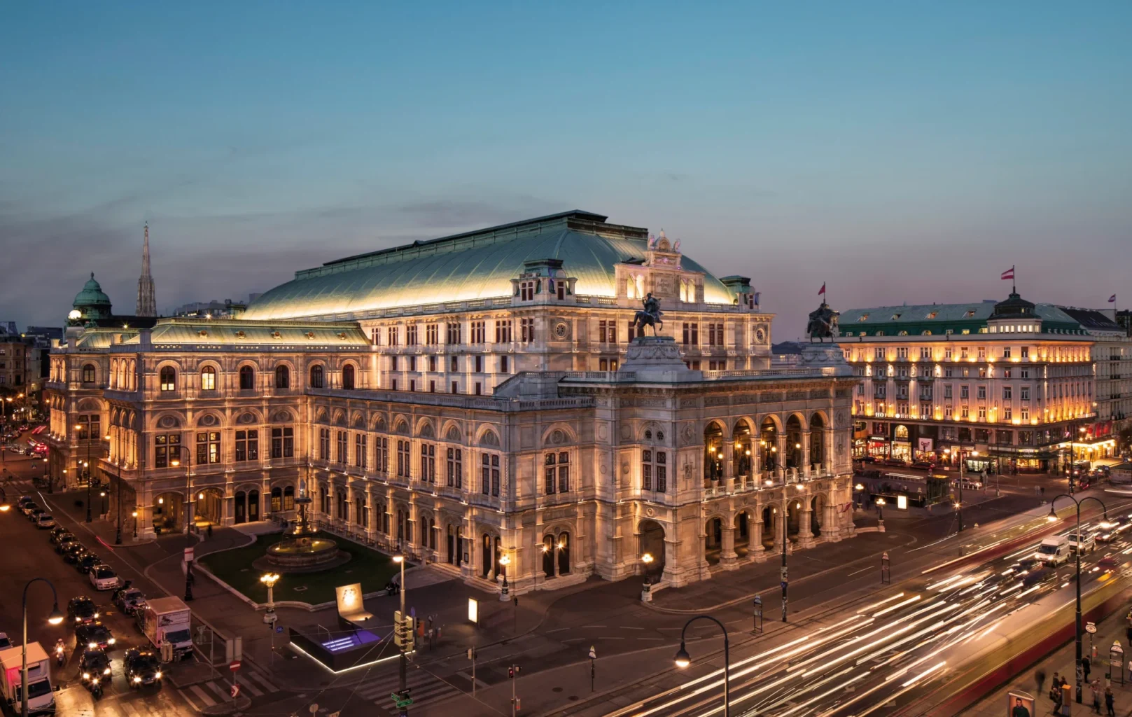 Opera House Vienna illuminated at dusk, with traffic lights and blurred car trails weaving past this iconic Vienna attraction.